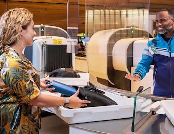 Luchthavenbeveiliger en passagier die bezig zijn met een controle